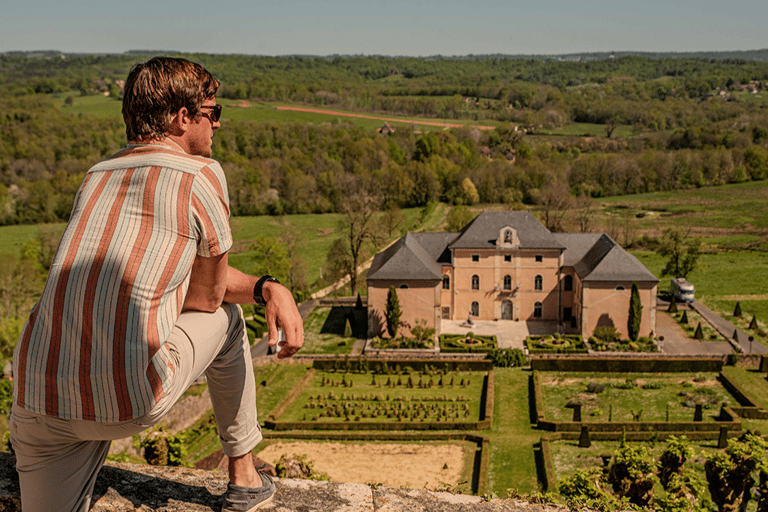 A man overlooking a historic French chateau and manicured gardens in the countryside.