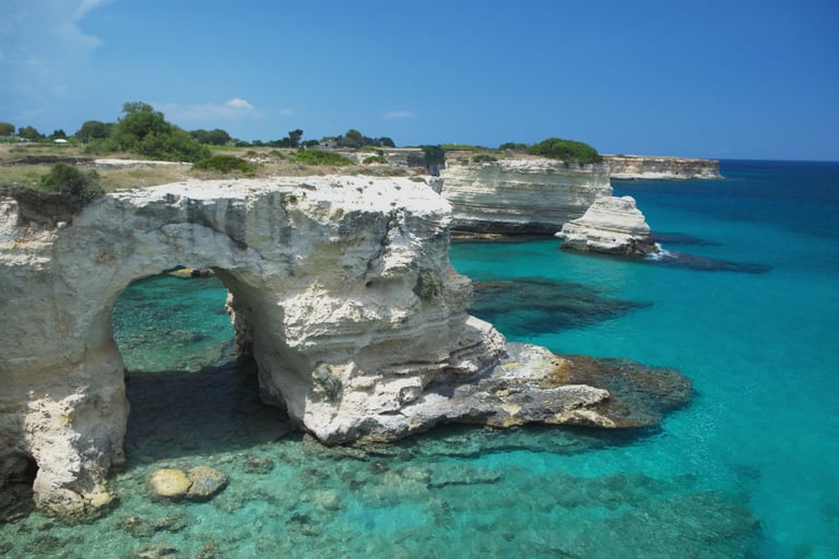 White limestone cliffs and natural arch over crystal clear turquoise sea at Torre dell'Orso, Puglia.