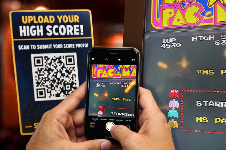 a person using using a QR code to snap and send their high score on pacman