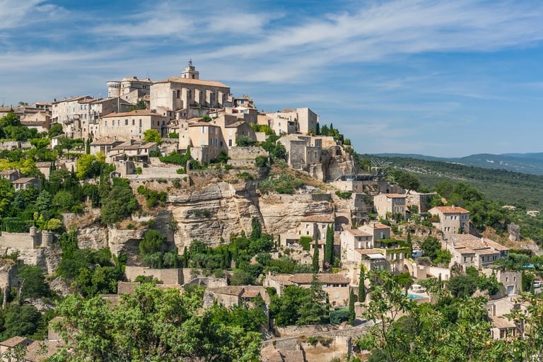 Scenic view of the hilltop village of Gordes in Provence, France, featuring stone houses and a blue sky.