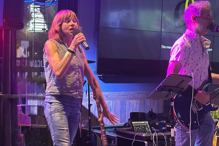 Tracy and Dan performing live music on a stage with neon lighting.