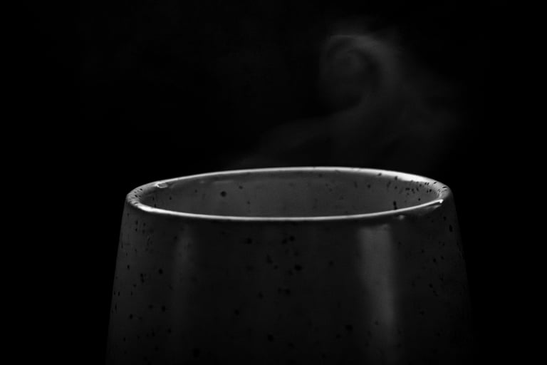 Steam rising from a dark ceramic cup against a black background