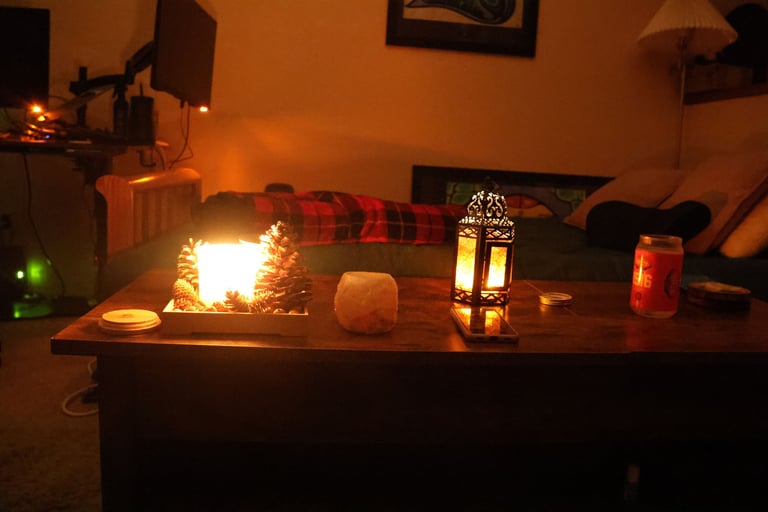 Low light candlelit living room with candles glowing on a wooden table and a sofa in the background.