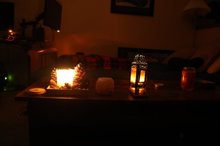 Low light candlelit living room with candles glowing on a wooden table and a sofa in the background.