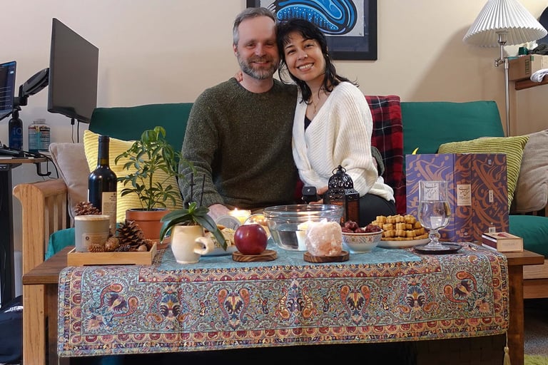 Couple sitting on a couch behind a decorated table, smiling at the camera