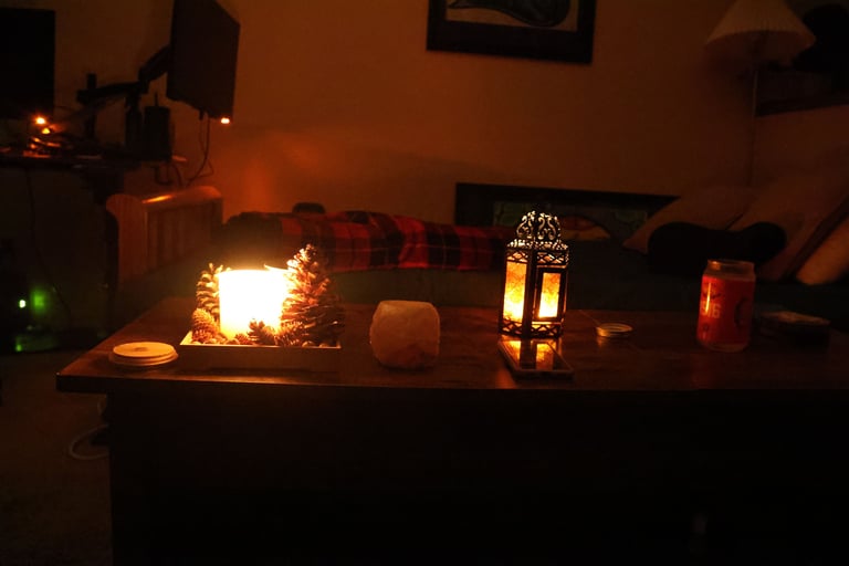 Low light candlelit living room with candles glowing on a wooden table and a sofa in the background.