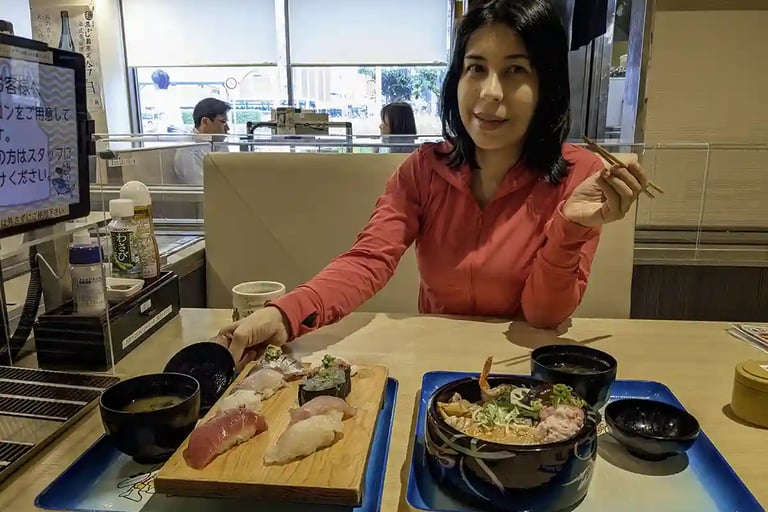 Woman eating sushi and noodle soup at a restaurant table
