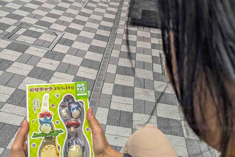 Woman holding a Studio Ghibli souvenir featuring Totoro characters while exploring Osaka, Japan.