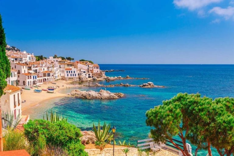 Scenic view of Calella de Palafrugell coastal village on Costa Brava with turquoise water and white houses.