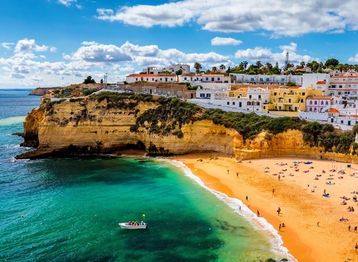 Scenic view of Carvoeiro beach in Portugal with golden sand, turquoise water, and white houses.