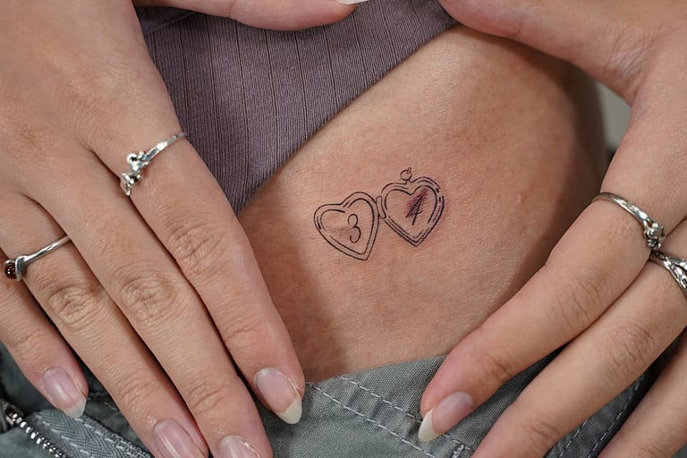 Tatuaje fineline en Madrid de dos corazones estilo medallón con iniciales en trazo 