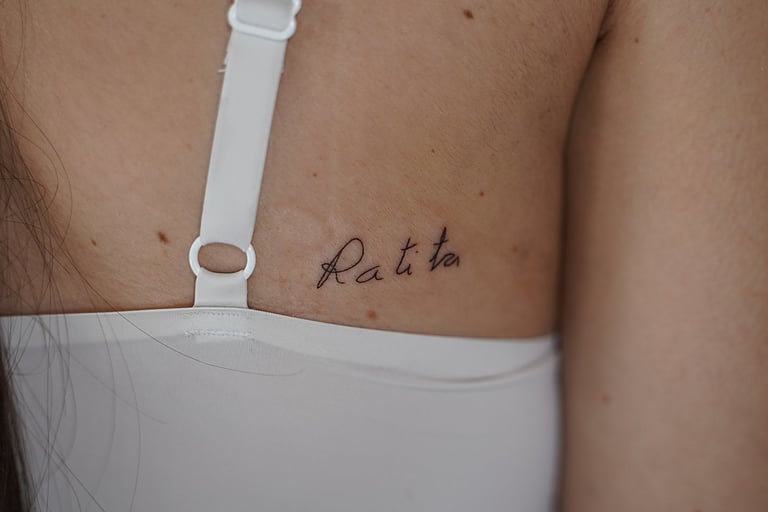 Tatuaje fineline en Madrid con lettering Ratita en cursiva fina en la espalda