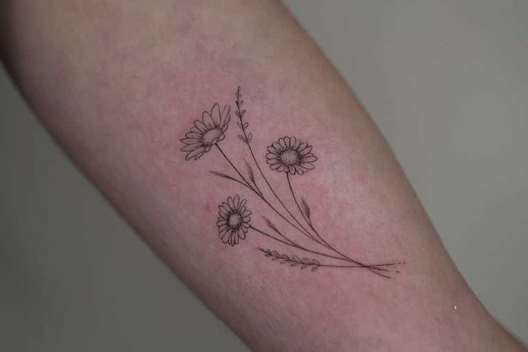 Tatuaje fineline en Madrid de tres margaritas silvestres con espigas y tallos en composición