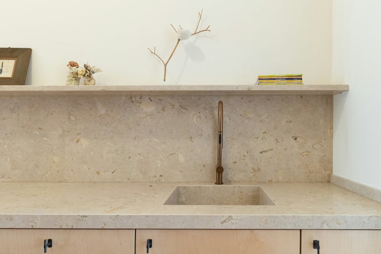 Kitchen where the stone worktop continues up the wall as a restrained splashback.
