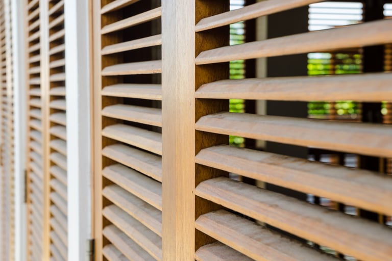 Filtered morning light through shutters in a Mediterranean bedroom.