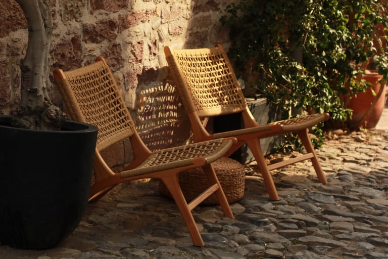 Weathered teak and matte metal furniture on a French Mediterranean terrace.