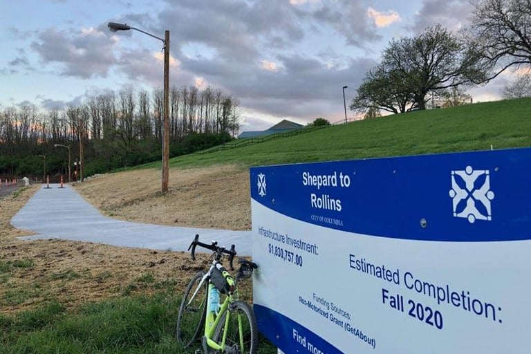 Paved trail with a sign reading "Shepard to Rollins, Estimated Completion: Fall 2020"