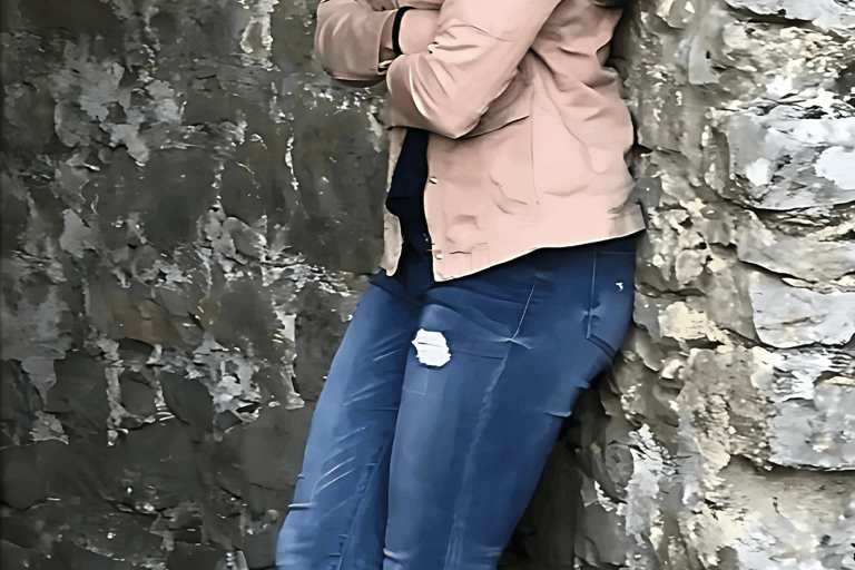 a woman standing in front of a stone wall