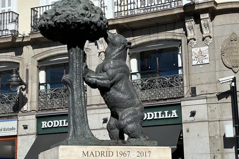 A statue of a bear leaning against a madroño tree