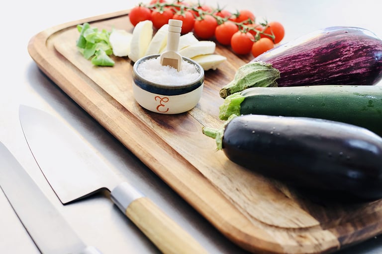 Légumes de saison et petit pot de fleur de sel posés sur une planche à découper
