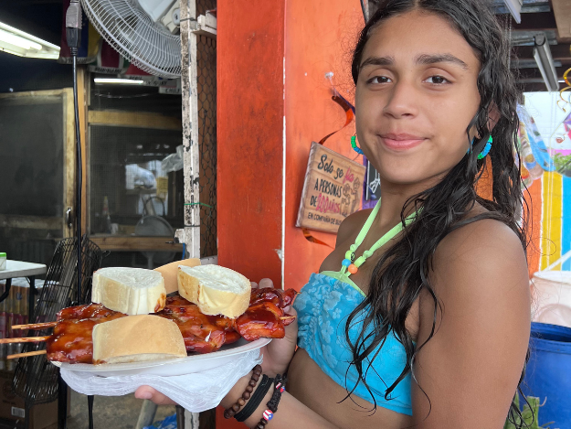 a girl holding a plate of Puerto Rican pinchos