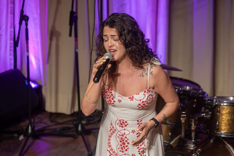 a woman in a white dress singing into a microphone