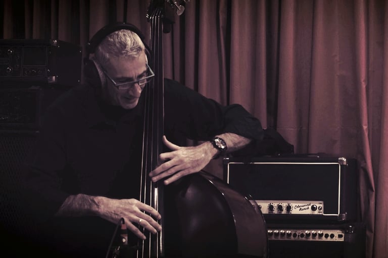 Professional musician playing a double bass in a recording studio with vintage amplifiers.