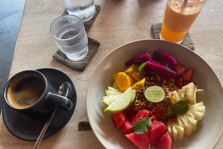 Petit-déjeuner chez Muda à Canggu : assiette de fruits colorés, jus de fruits frais et café 