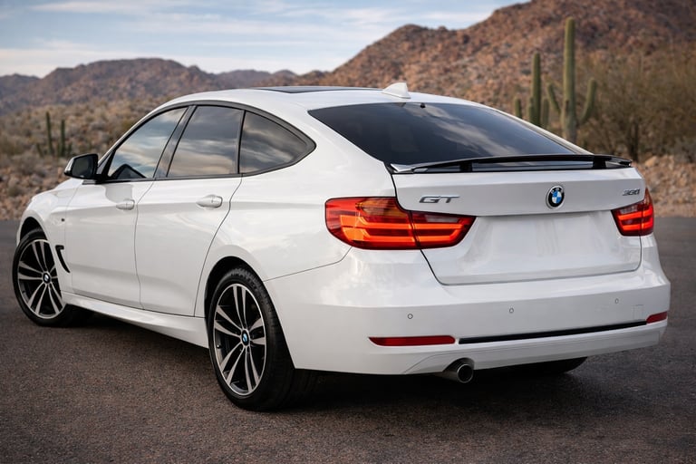 BMW 320i GT branca com aerofólio ativo em destaque vista traseira em cenário aberto