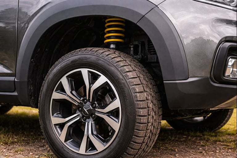 Detalhe da roda e suspensão de SUV, mostrando maior altura do solo e espaço entre pneu e lataria