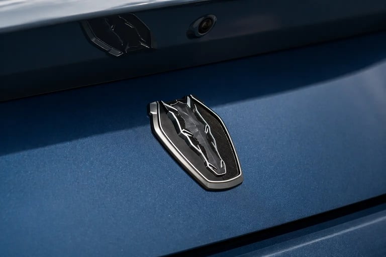 Emblema traseiro do Ford Mustang em close com acabamento azul metálico