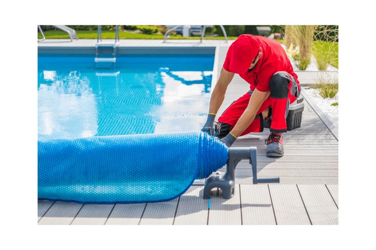 Pool tech in red uniform kneeling poolside getting ready to unroll the pool cover