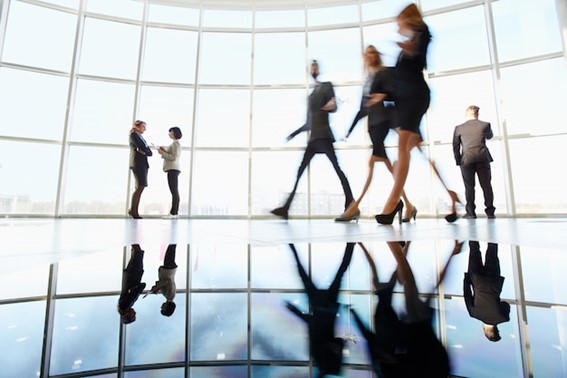 a group of business people walking through a large glass window