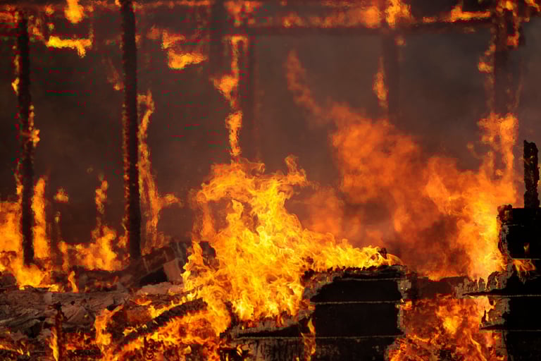 alt="Close-up of active house fire with visible flames and burning debris"