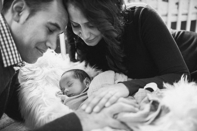 a man and woman holding a baby in a blanket