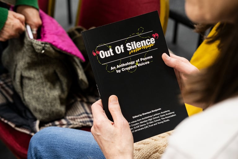 a person holding a book with black cover and white text decorated with colourful doodles