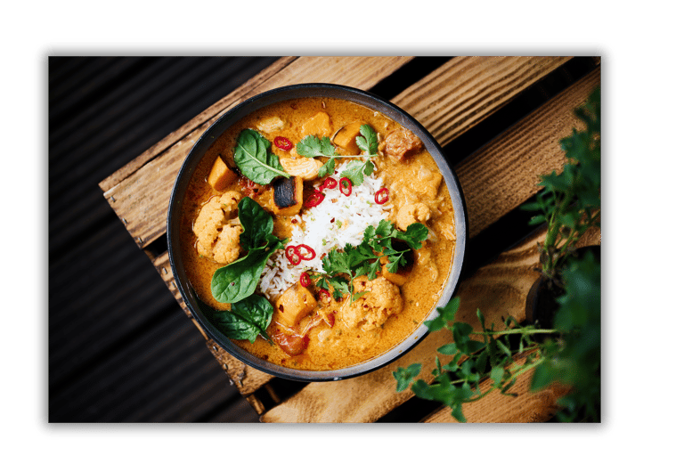 a bowl of food with a wooden table and a potted plant