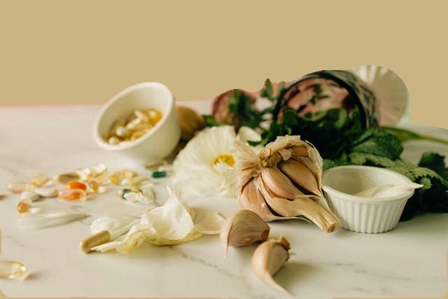 Fresh garlic cloves and herbal supplement capsules on a marble surface for natural wellness.
