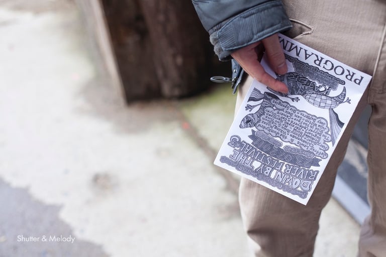 Ein Mann hält ein Programm von Down By The River 2011 in der Hand.