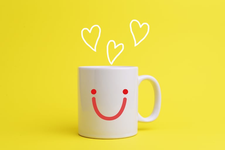 Una taza de café con una cara sonriente en el frontal y en vez de humo salen corazones