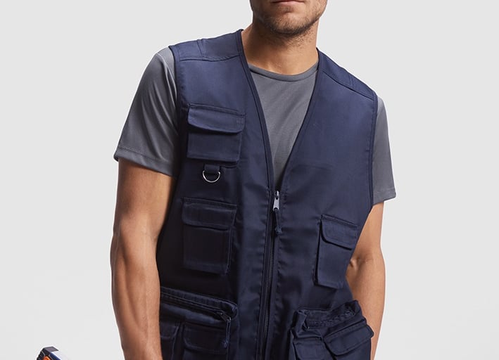 Imagen de un torso que porta una camiseta de poliéster gris y un chaleco multibolsillos azul marino