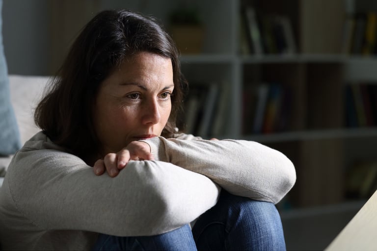 Woman sitting alone feeling emotionally exhausted, anxious and overwhelmed by unexplained phenomenon