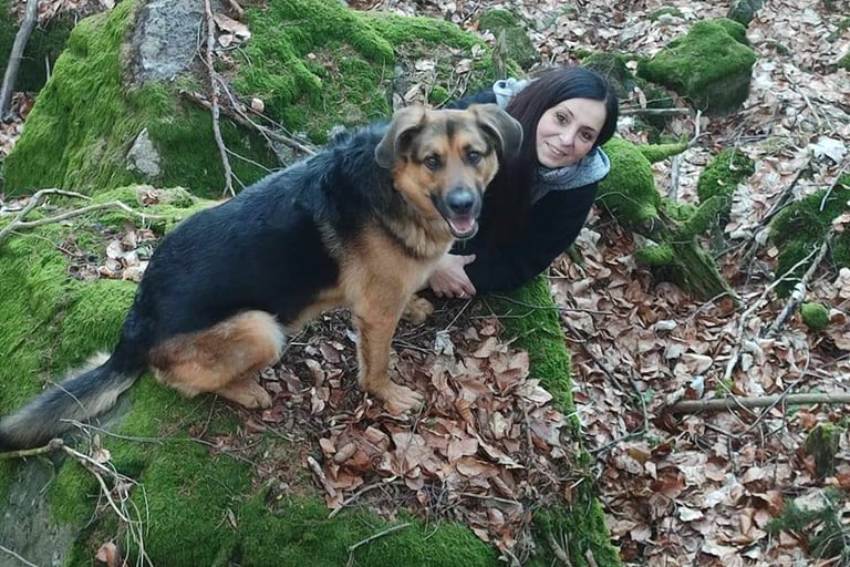 Kobieta z psem siedząca na kamieniu