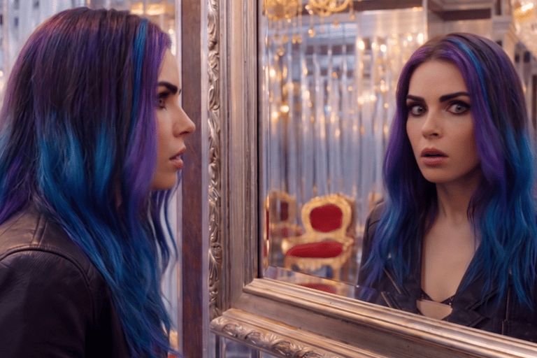 A woman with vibrant purple and blue hair looks surprised while staring at her reflection in a luxury mirror.