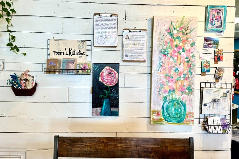 a coffee shop wall containing original art, greeting cards, bookmarks, and journals on display