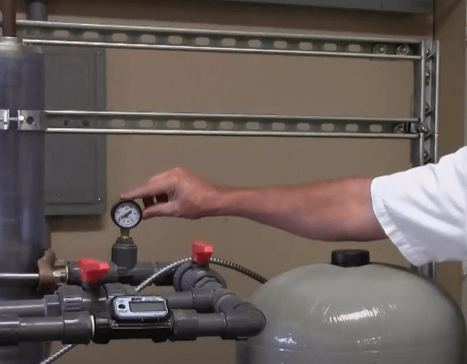 Man pointing to water pressure tank gauge
