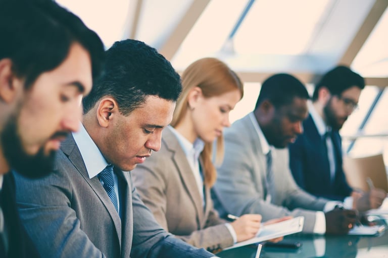 Ejecutivos tomando notas minuciosas durante una sesión intensiva de capacitación sobre la cultura le