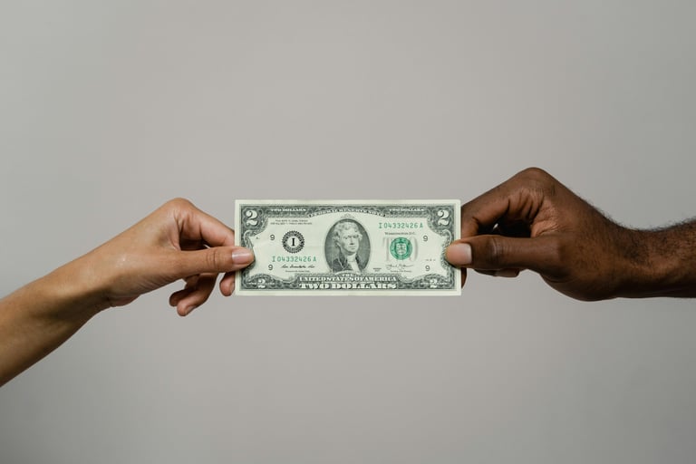 Two people holding a two dollar bill