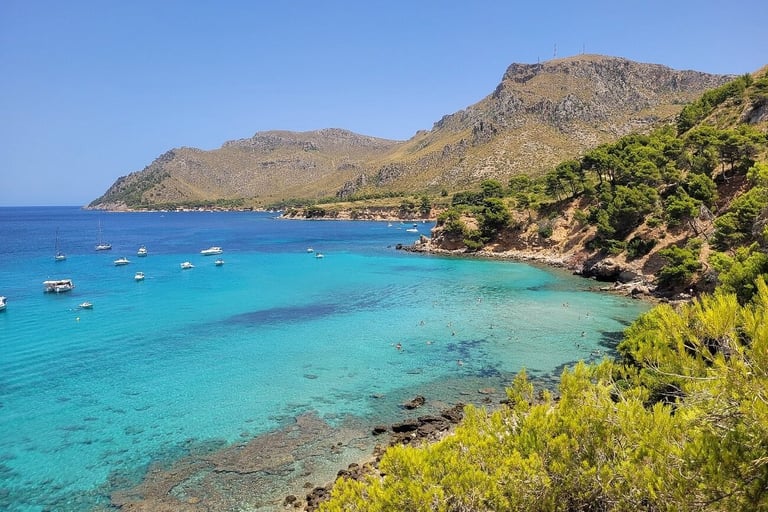 Vista de Cala Na Clara con aguas turquesas y barcos fondeados – excursión en barco desde Alcudia