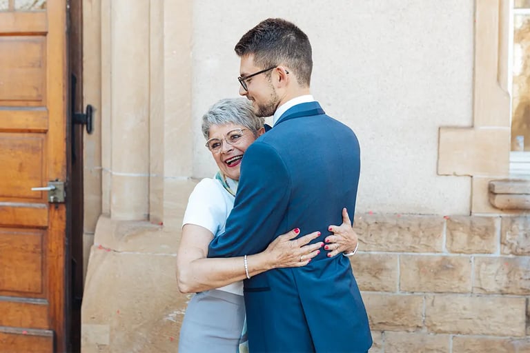 Marié en costume qui étreint sa maman à la sortie de la mairie